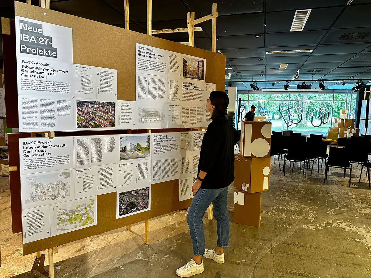 Person steht vor IBA'27-Projektausstellung mit mehreren Infotafeln zu neuen Stadtentwicklungsprojekten